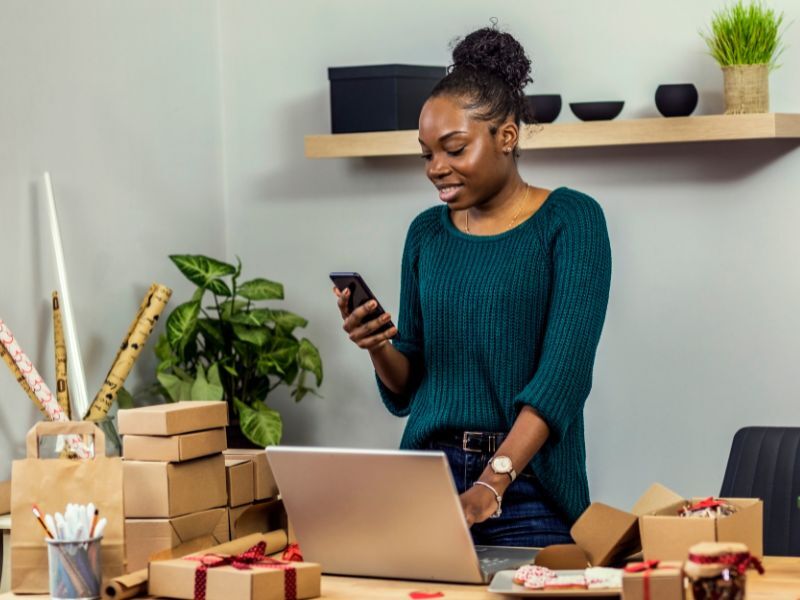 A woman markets her small business with a laptop and cell phone